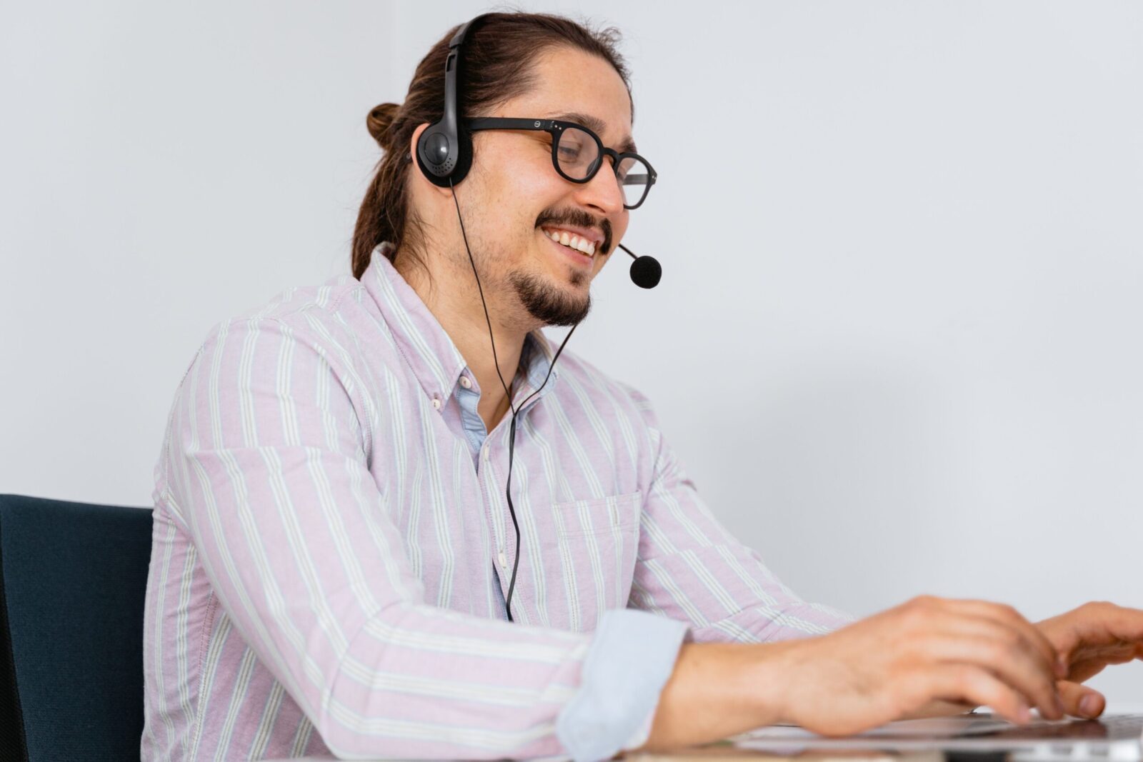 Smiling call center agent wearing headset assisting customers indoors.